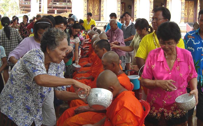 femme thailandaise versant de l'eau sur la tête d'un moine à Bangkok